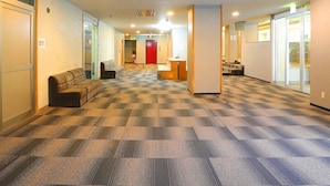 A hotel lobby with a checkered carpet, a reception desk, a red door, and a seating area with a sofa and armchairs. - Ryuo Mountain Hotel (Yamanouchi)