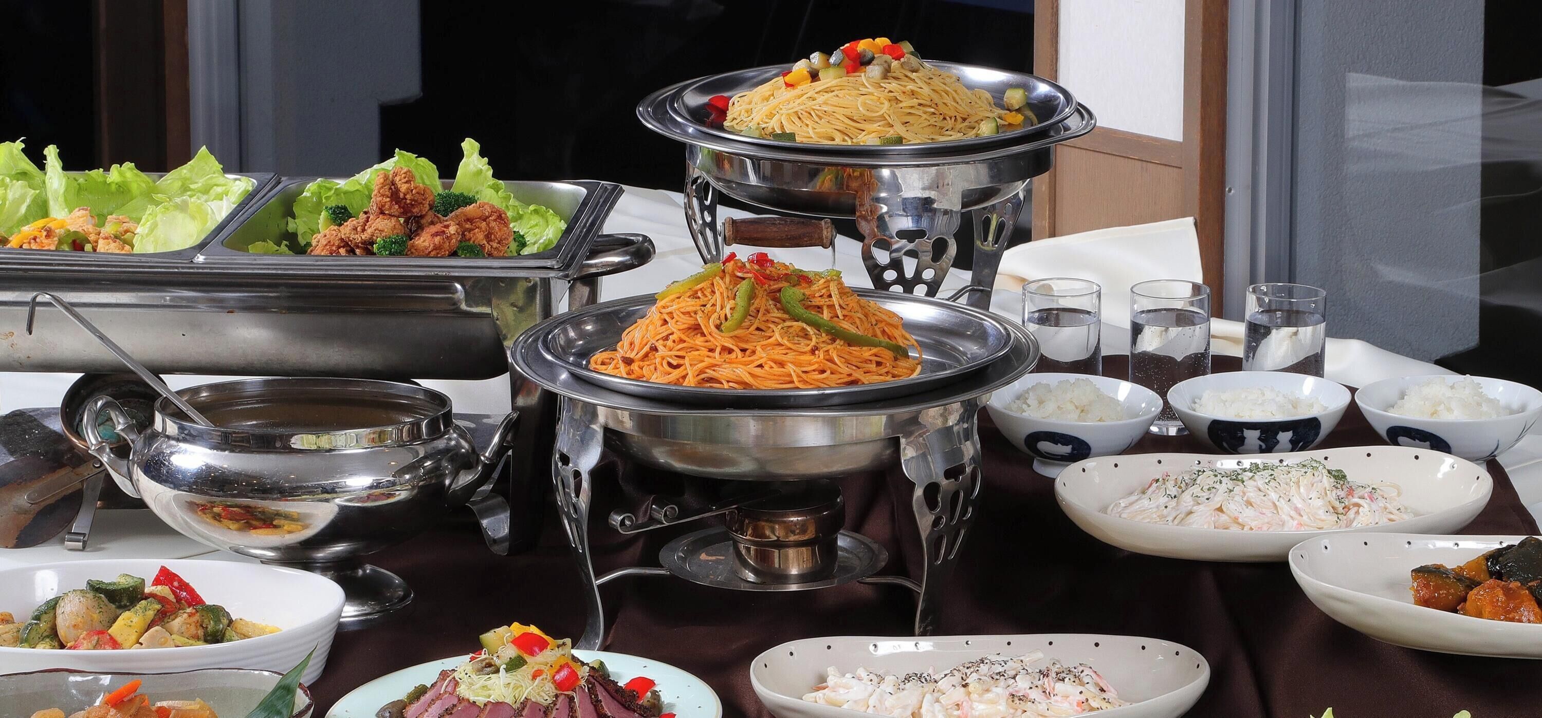 A buffet table with various dishes including noodles, vegetables, and seafood.