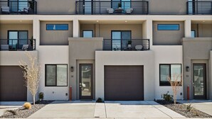 A modern multi-story residential building with balconies, large windows, and a garage. - St. George Getaway, Brand New 5 BD Luxury Townhome (St. George)