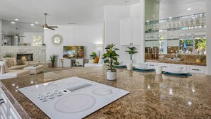 A modern kitchen with granite countertops, a built-in oven, and a glass wine rack. - Pickle+Basketball|Billiards|9bdr+6bath|Saltwater (Desert Hot Springs)