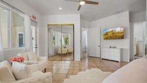 A spacious room with a large bed, a seating area with a sofa and chairs, a dining table, and a TV mounted on the wall. - Pickle+Basketball|Billiards|9bdr+6bath|Saltwater (Desert Hot Springs)