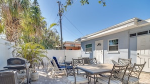 Un patio con mobiliario exterior, una parrilla y una palmera.