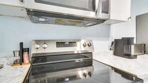 Una cocina con horno de acero inoxidable, microondas y cafetera.