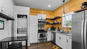 A modern kitchen with white cabinets, stainless steel appliances, a wooden ceiling, and a black dining table with chairs. - 70" TV, pool table, darts, 10 minutes from Wildlife Boat Ramp + Board & Batten (Lexington)