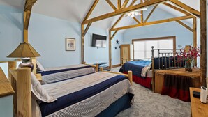 A bedroom with two beds, wooden beams, a ceiling fan, a TV, and a window with blinds. - 70" TV, pool table, darts, 10 minutes from Wildlife Boat Ramp + Board & Batten (Lexington)