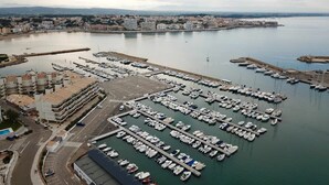 Un port de plaisance où sont amarrés de nombreux bateaux, entouré d’immeubles résidentiels et bordé d’une route menant au port.