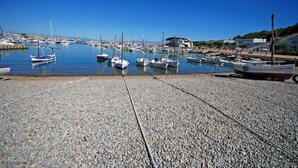 Un port de plaisance avec des bateaux amarrés et une plage de galets au premier plan.