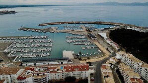 An aerial view of a marina with numerous boats docked, a swimming pool, and residential buildings with balconies. - Apartaments l'Escala Centre  3 (Escala, L')