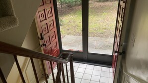 Eine Treppe führt zu einer Glastür mit Blick auf einen Garten.