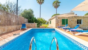 Ein Swimmingpool mit blauen Fliesen, einer Steinmauer und einem Holzdeck.