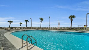 A swimming pool with a clear blue water, surrounded by palm trees and lounge chairs. - Beach front condo; great location; with pool  (Orange Beach)