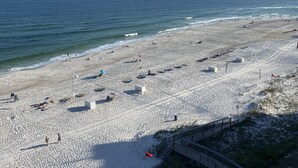 A beach with a wooden boardwalk leading to a building. - Beach front condo; great location; with pool  (Orange Beach)