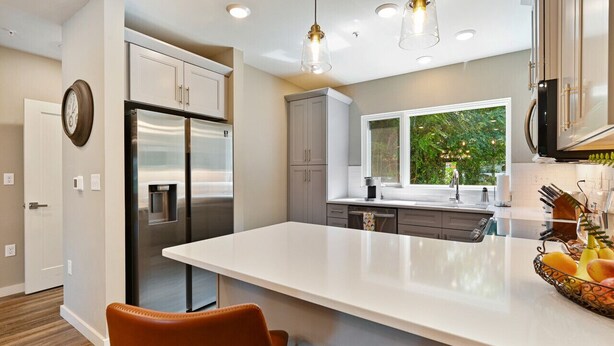 Una cucina moderna con elettrodomestici in acciaio inox, una grande isola e vista sul verde.
