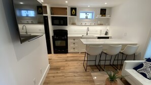 Una cucina moderna con mobili bianchi, un piano cottura nero e un'isola bianca con sgabelli da bar.