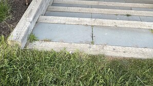 Un ponte di legno con tavolo e sedie, una porta gialla e un muro in mattoni.