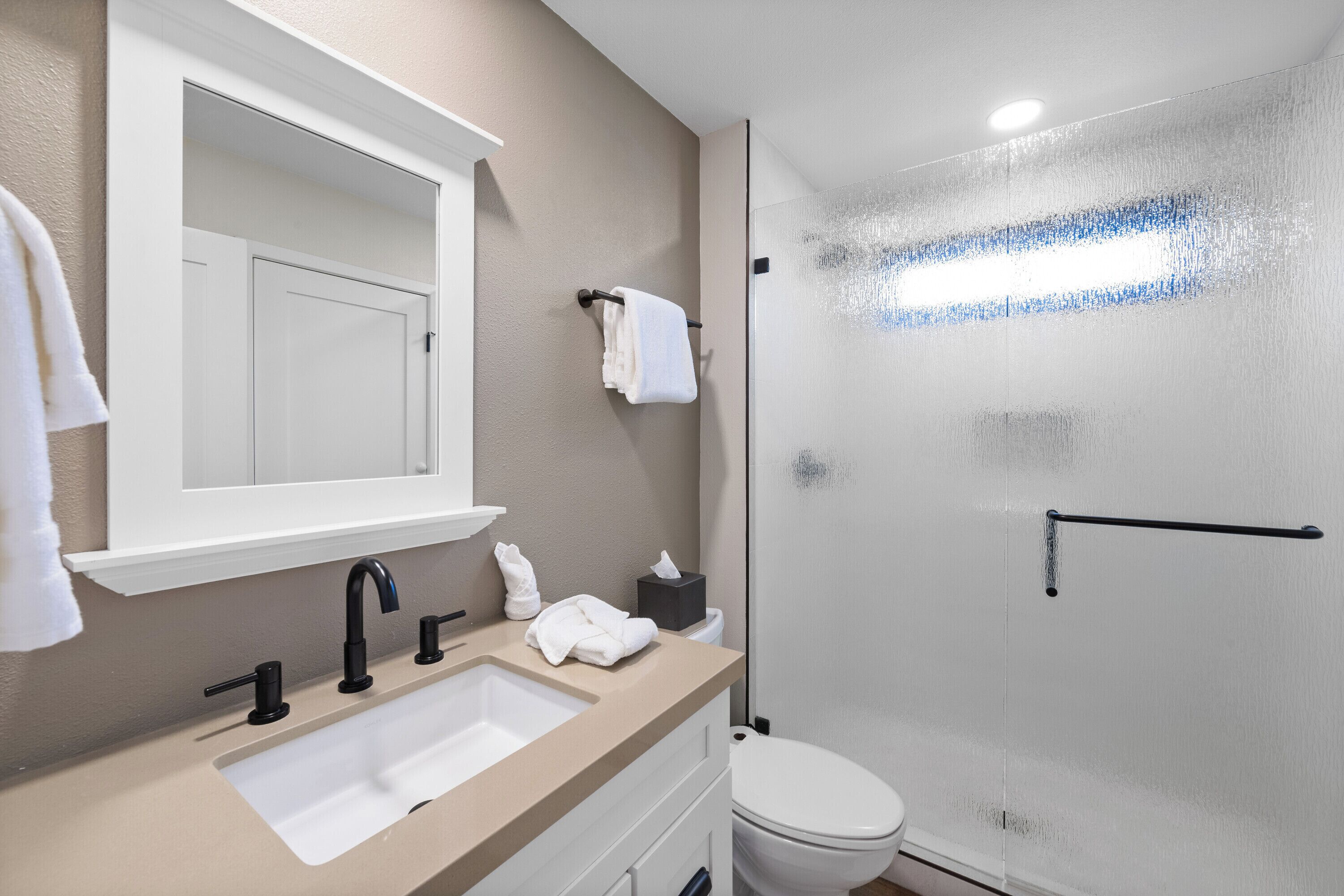 Et moderne badeværelse med vask, spejl og toilet.