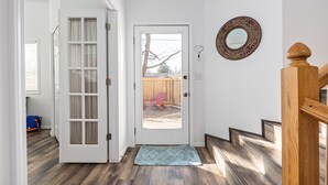 A wooden staircase leading to a door with a glass panel, a blue rug, and a decorative mirror on the wall. - Cozy House Near Boise State University, Downtown and Boise River Greenbelt. (Boise)