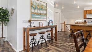 A modern kitchen with a wooden island, bar stools, and a large painting on the wall. - Cozy House Near Boise State University, Downtown and Boise River Greenbelt. (Boise)