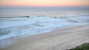 A beach with waves and a sunset.