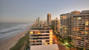 A high-rise hotel with multiple floors, balconies, and a view of the beach and ocean.