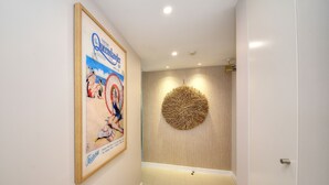 A hallway with a framed poster, a textured wall decoration, and a door.