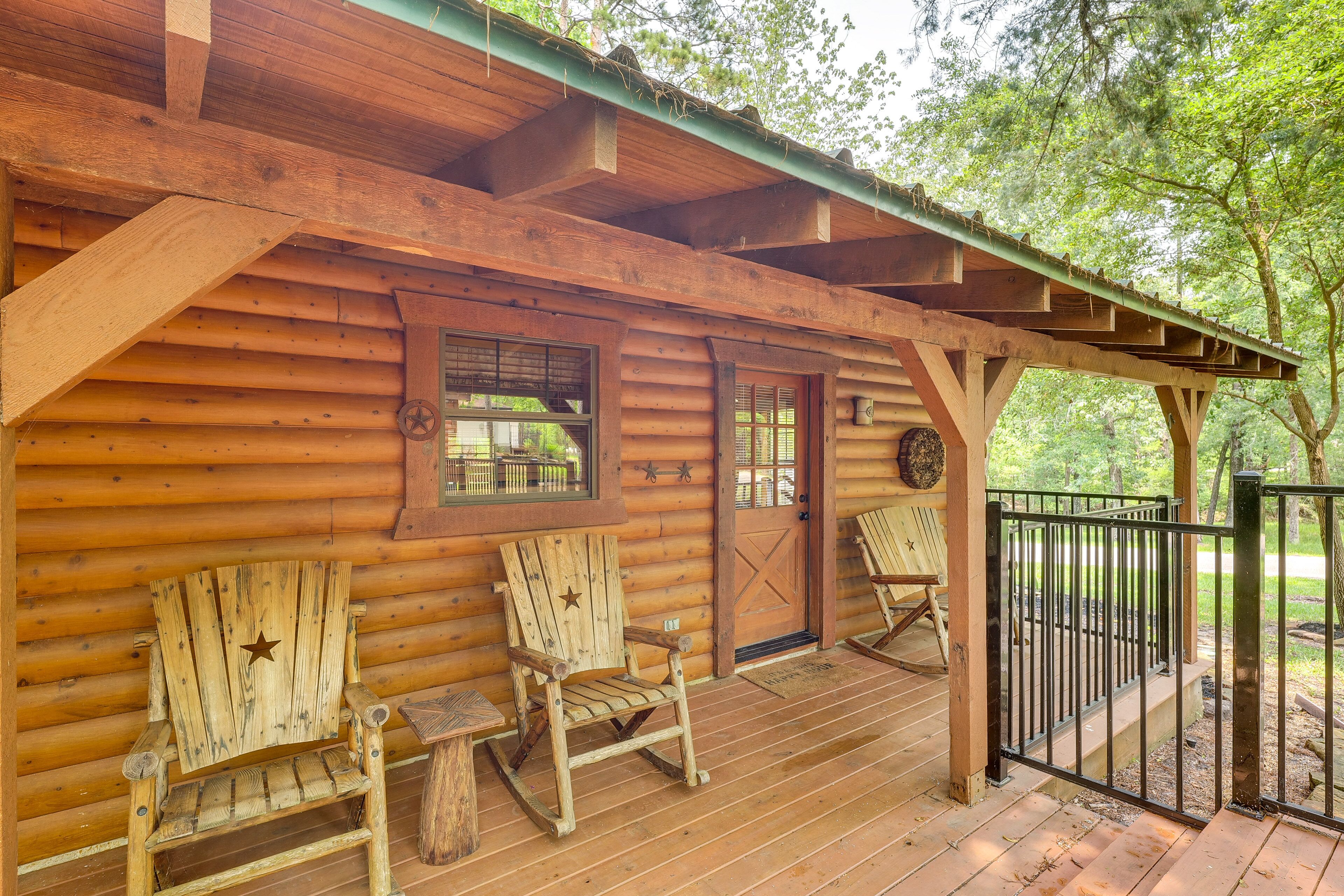A wooden cabin with a porch, two rocking chairs, and a metal gate.