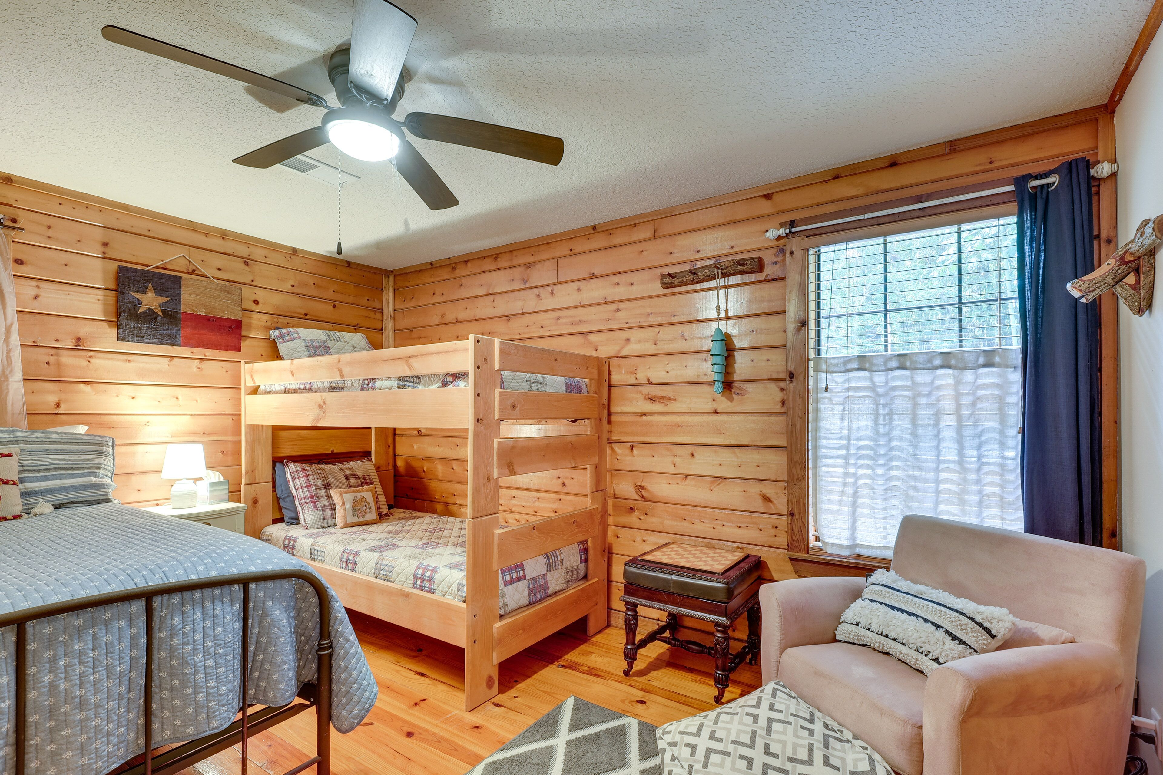 Ein gemütliches Cabin-Zimmer mit einem Etagenbett, einem Einzelbett, einem Sessel und einem Deckenventilator.