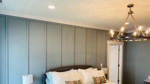 A neatly arranged bedroom with a large bed, a bedside lamp, and a chandelier.