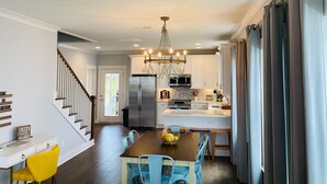 A modern kitchen with a central island, stainless steel appliances, and a chandelier.