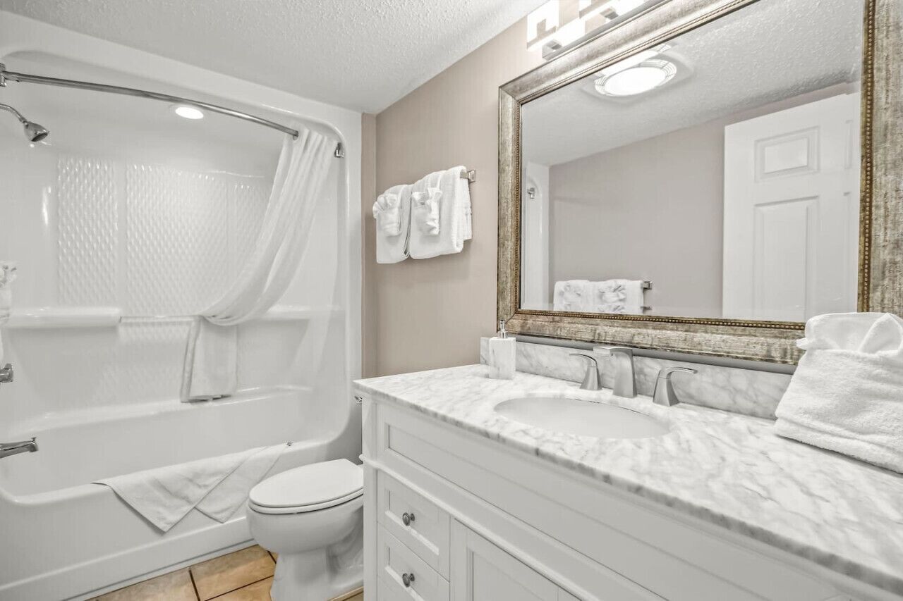 A bathroom with a bathtub, toilet, and a vanity with a mirror.