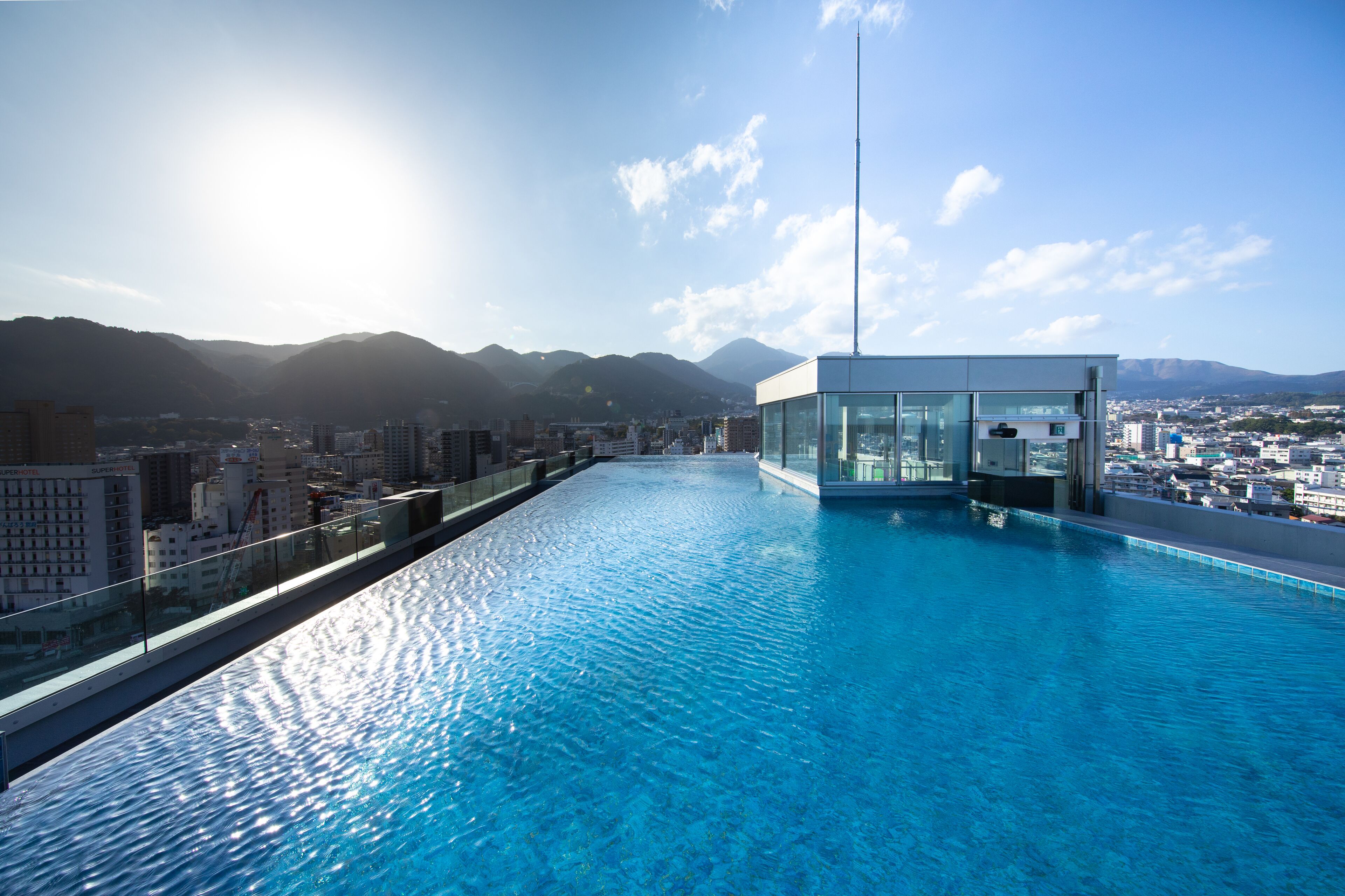 A rooftop infinity pool with a glass enclosure, offering a cityscape view.