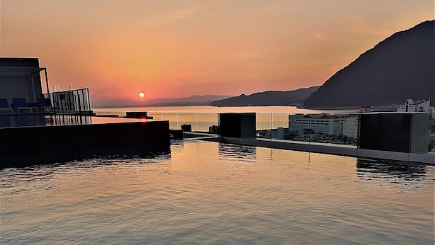 Ett hotell vid vattnet med utsikt över solnedgången, en pool och en bar.