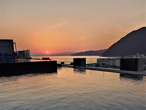 A waterfront hotel with a sunset view, a pool, and a bar area.
