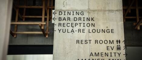 A directional sign with arrows indicating the locations of dining, bar drink, reception, Yula-Re Lounge, rest room, EV, amenity, and Amanek Inn.