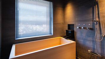 Un baño moderno con una bañera grande, ducha y ventana con persianas.