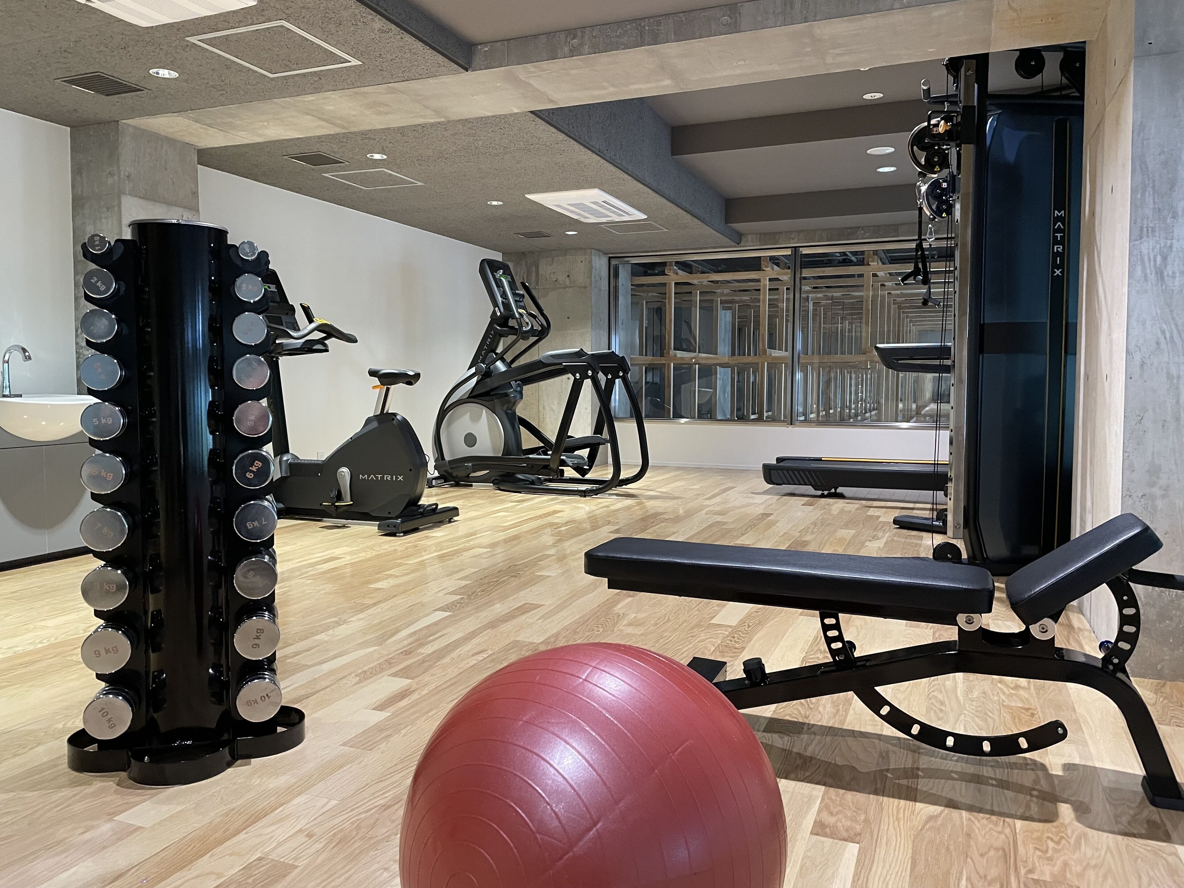 A gym with exercise equipment, a rowing machine, and a bench.