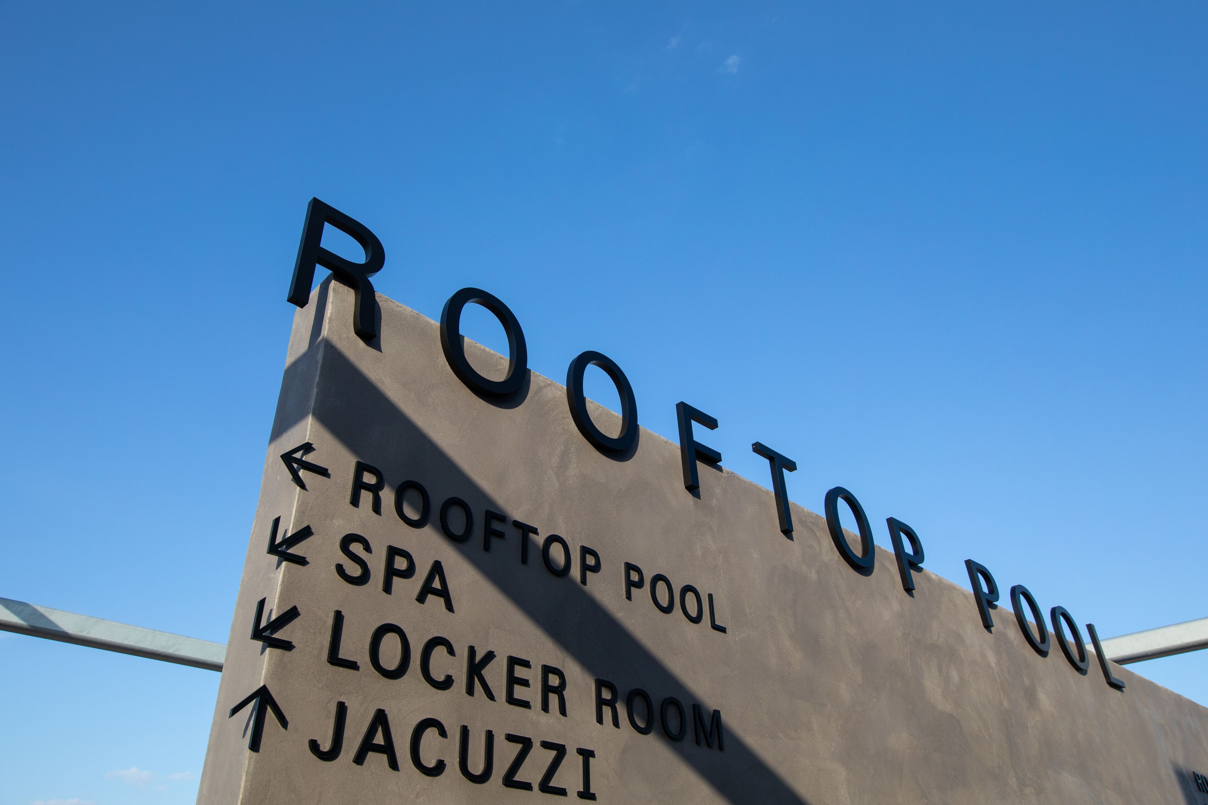A sign with directions to the rooftop pool, spa, locker room, and jacuzzi.