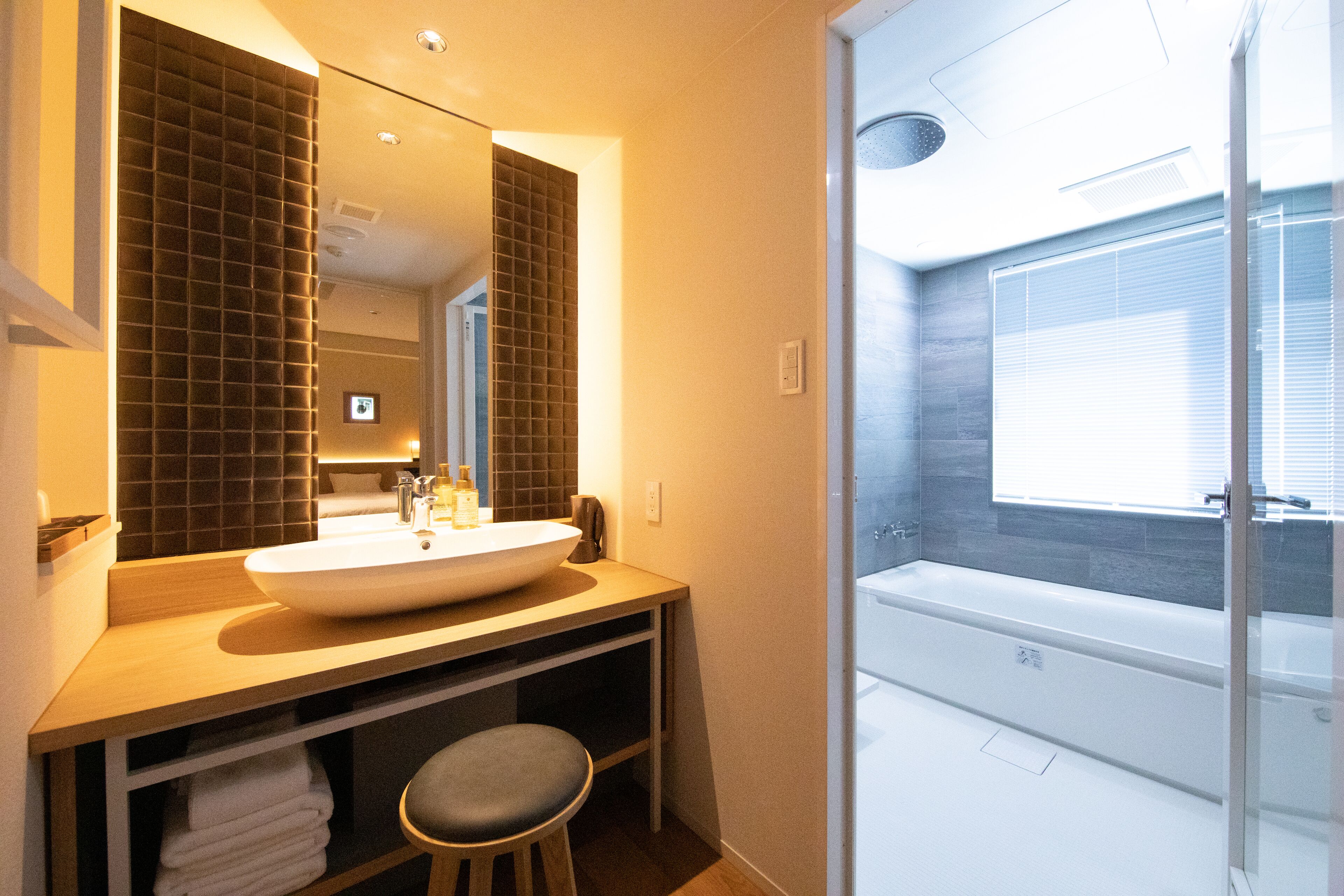 Un baño moderno con un lavamanos amplio, espejo y bañera.