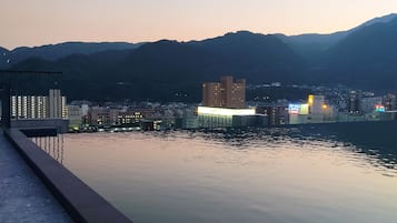 Une vue paisible sur le bord de l’eau, avec un bâtiment moderne et des montagnes en arrière-plan.