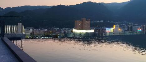 Une vue paisible sur le bord de l’eau, avec un bâtiment moderne et des montagnes en arrière-plan.