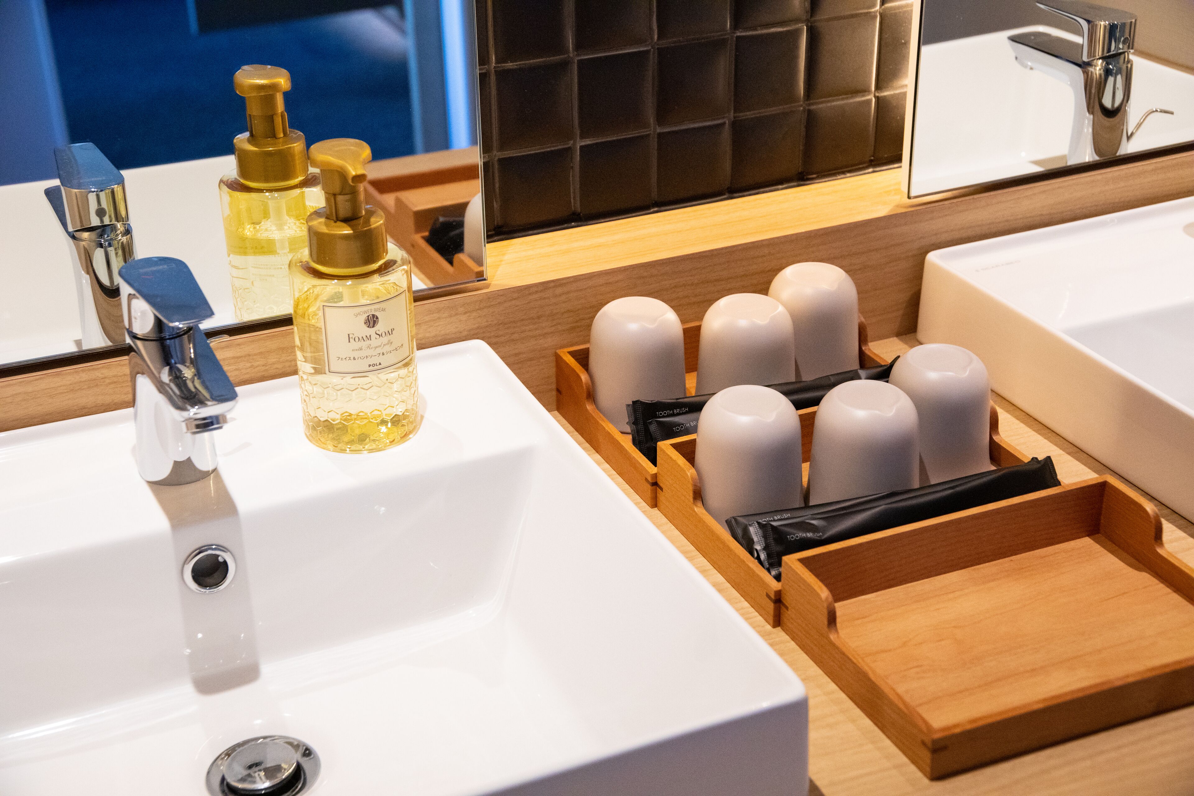 Een badkamer met een wit wastafel, een spiegel en toiletartikelen, waaronder zeep en tandenborstels.
