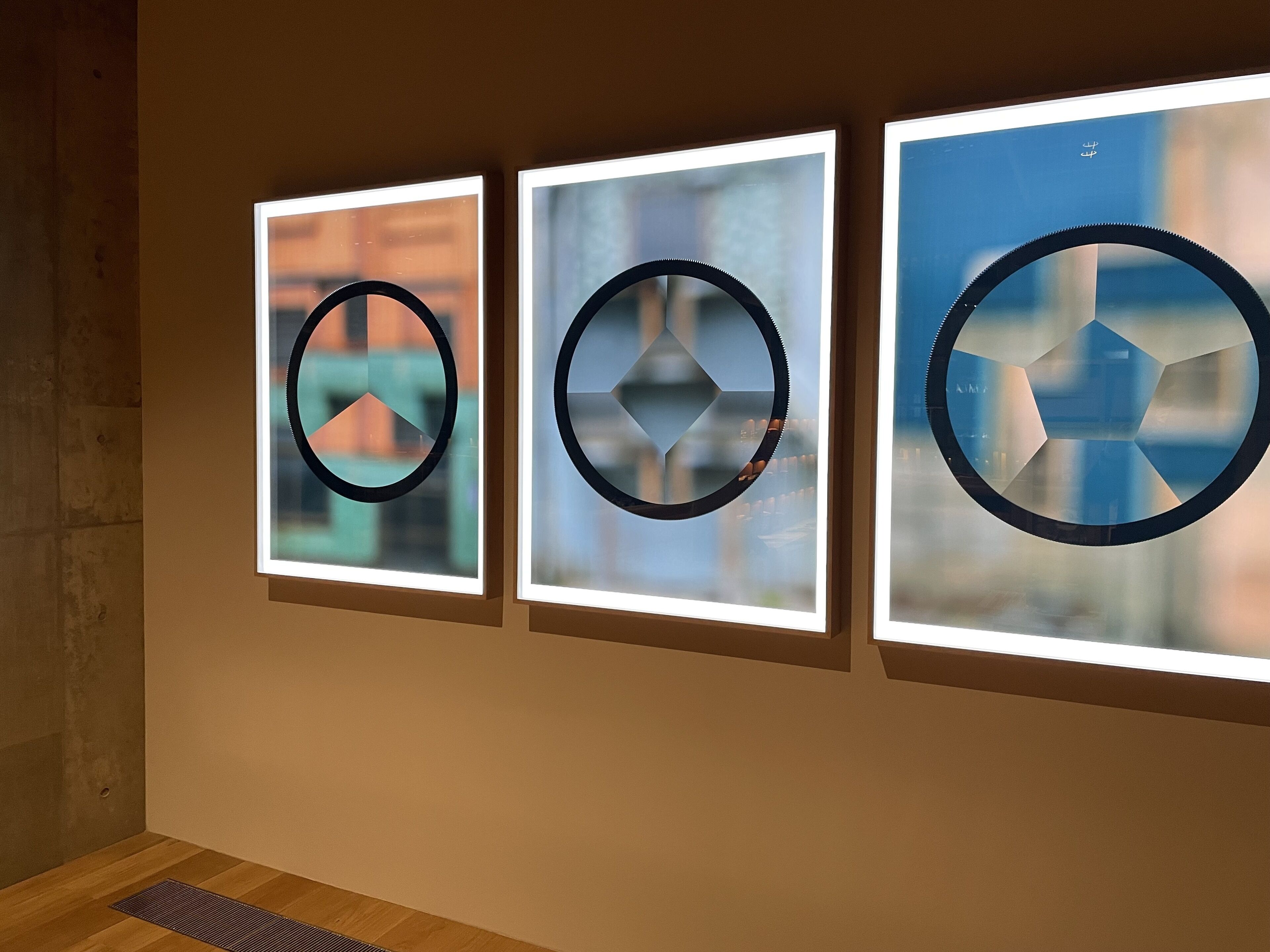 Three framed artworks with circular designs on a wall.
