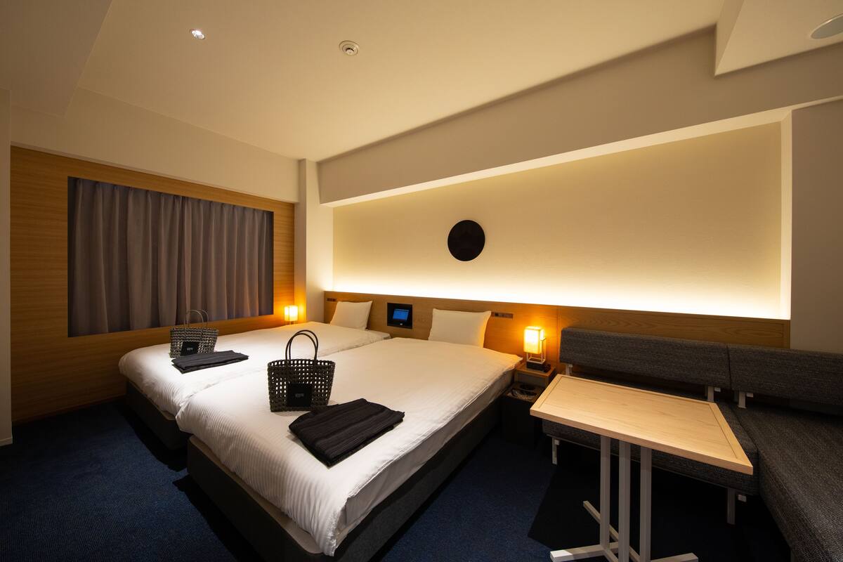 A hotel room with a large bed, bedside tables, a desk, and a wall-mounted TV.