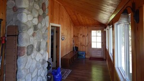 Ein Holzinnenraum mit Steinwand, Holzboden und großen Fenstern.