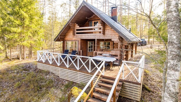 A log cabin with a deck, outdoor seating, and a chimney.