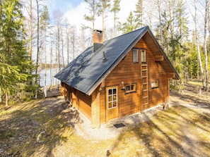 A wooden cabin with a sloped roof, a chimney, and a wooden deck. - Paapuuri by Interhome (Asikkala)