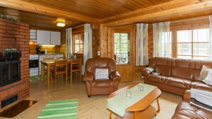 A cozy cabin interior with a fireplace, wooden furniture, and a dining area.