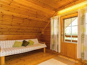 A wooden interior with a sofa, a door, and a window. - Paapuuri by Interhome (Asikkala)