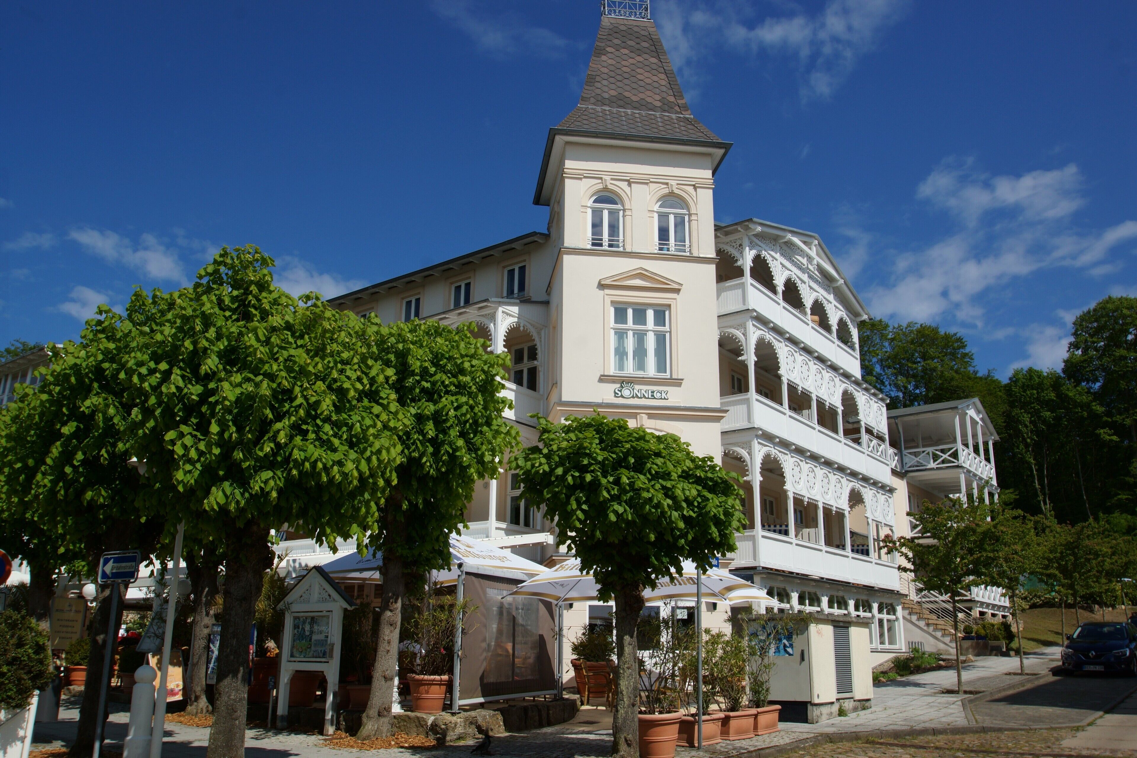 A historic building with a prominent tower, multiple balconies, and a covered outdoor seating area.
