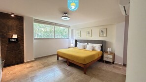 A bedroom with a bed, bedside tables, a window, and a wall-mounted radio.
